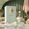 Una lujosa imagen del frasco de 100 ml de Juman Exclusive y su caja de regalo, sobre una superficie de mármol con perlas, pétalos de rosa y detalles decorativos.